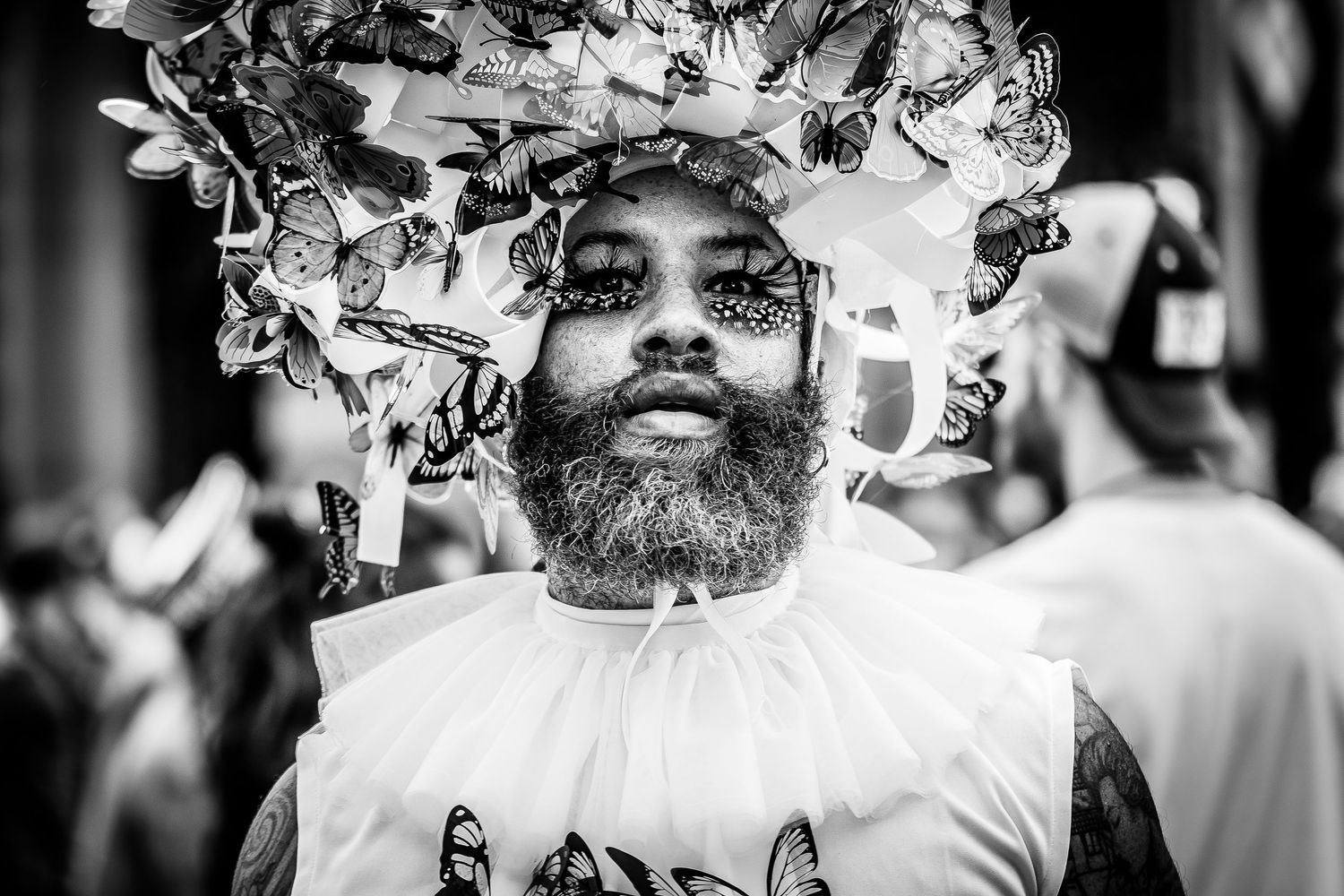Schwarz-Weiß-Porträt eines Mannes mit fantasievollem Kopfschmuck auf einer  Pride-Veranstaltung