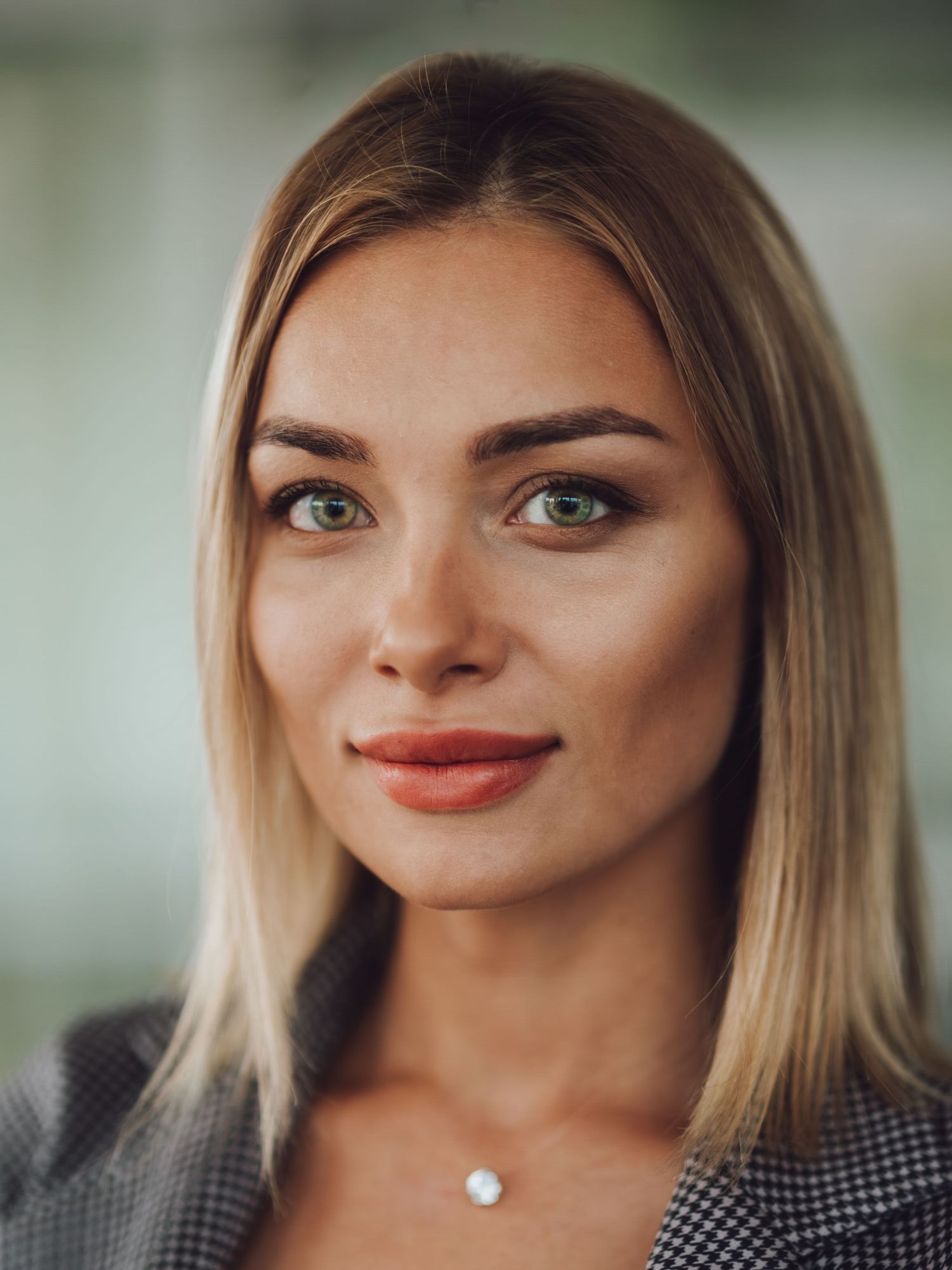 Young blonde woman with green eyes and subtle makeup wearing a blazer, professional headshot portrait photo.