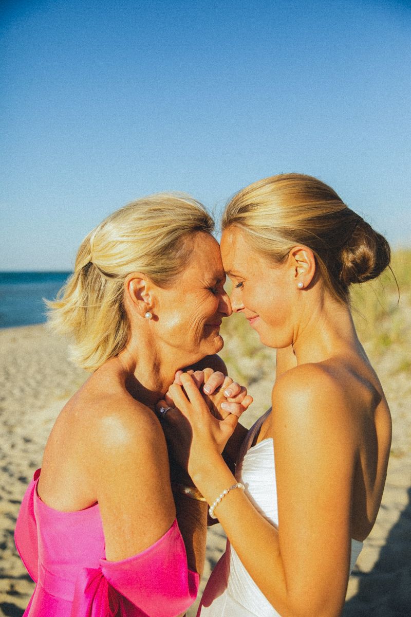 Two women share an emotional moment together on a sunny beach.