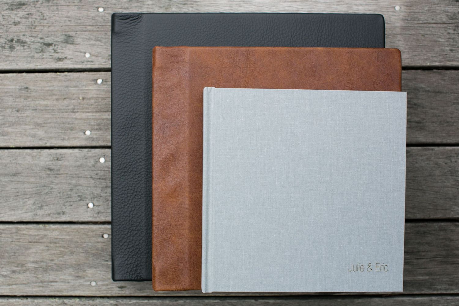 Stack of three photo albums in different colors on wooden surface.