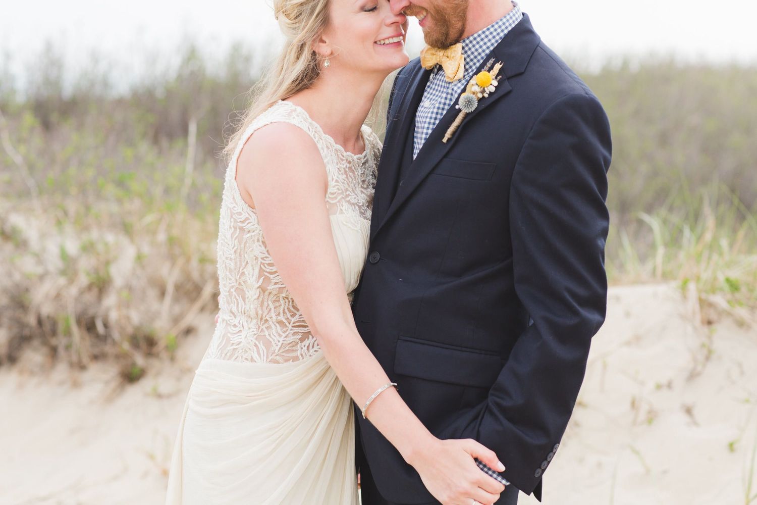 A romantic couple in wedding attire shares intimate moments together on a sandy beach during their special day.
