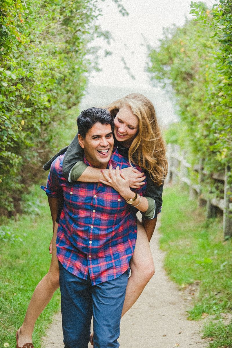 Playful couple sharing a fun moment on a tree-lined path in an orchard.