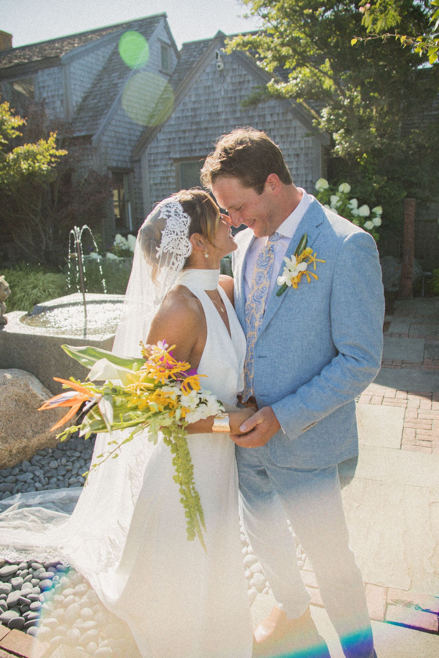 A couple shares an intimate moment during their outdoor wedding ceremony near a brick building.