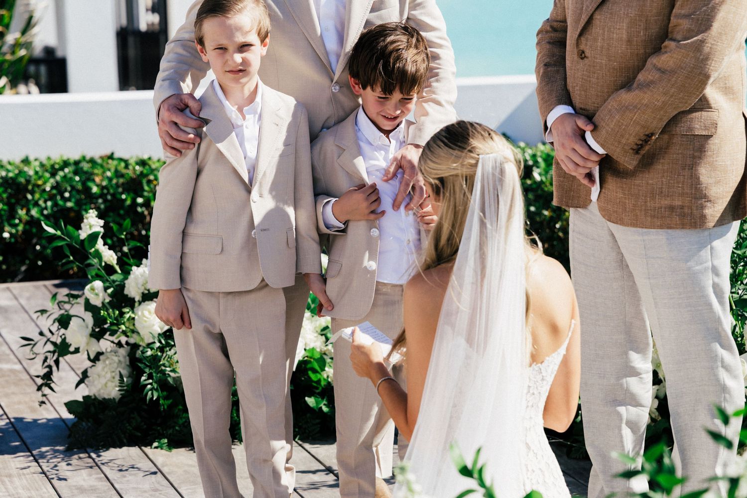 Wedding party gathered on a scenic coastal overlook with white floral arrangements and ocean views.