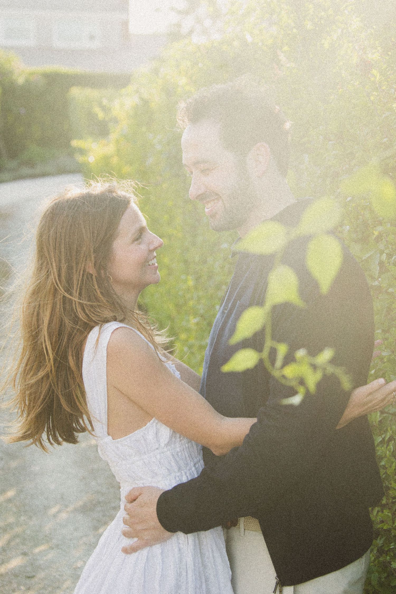 A couple shares tender moments in a sunlit garden setting during a romantic photoshoot.