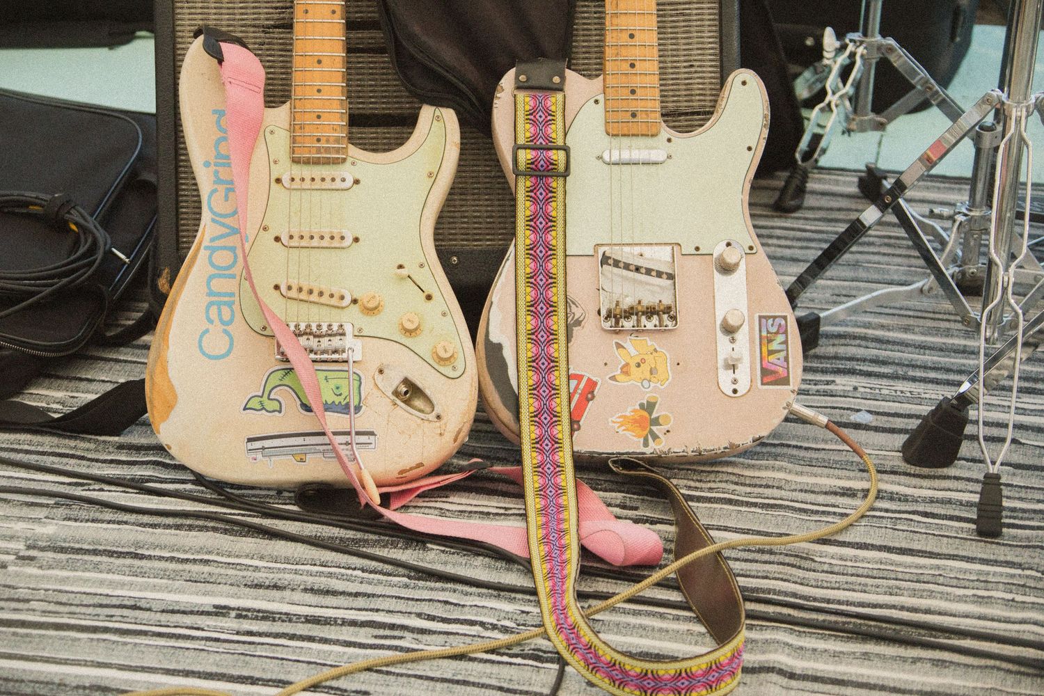 Two vintage-style electric guitars in pastel colors displayed on wooden deck.