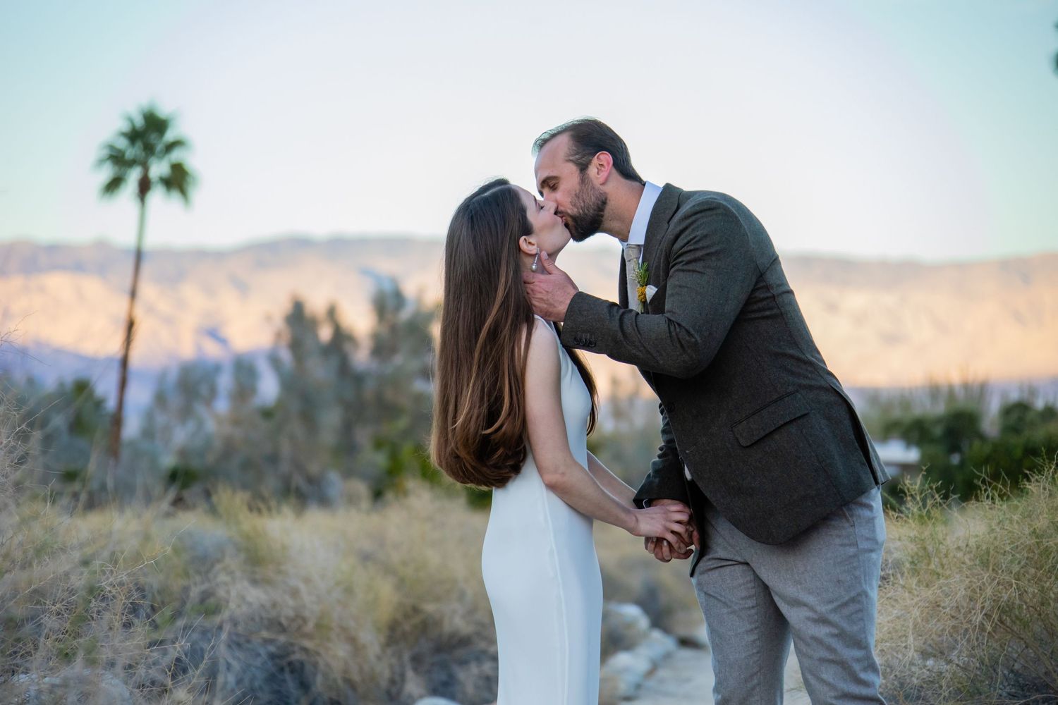 A couple shares romantic moments during their desert wedding photoshoot at sunset.