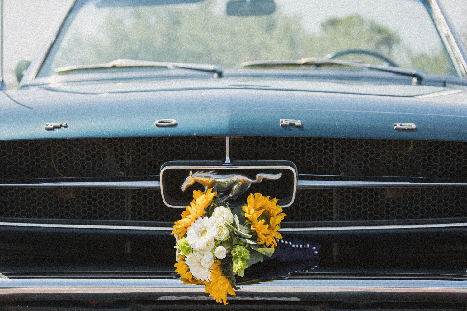 Classic black vintage car decorated with yellow sunflowers on dashboard.