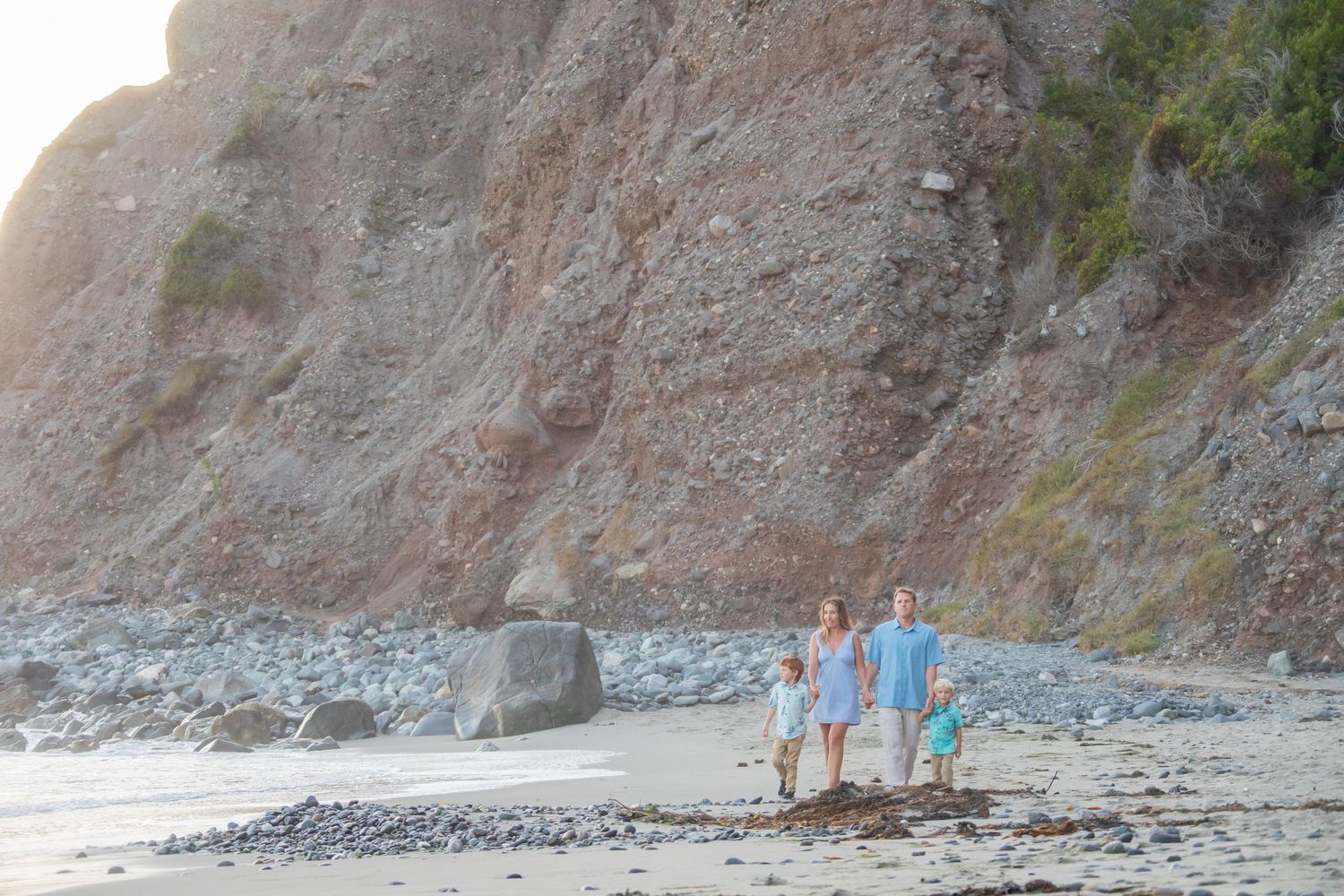 Wide view of a rocky coastline with steep cliffs and ocean waves.
