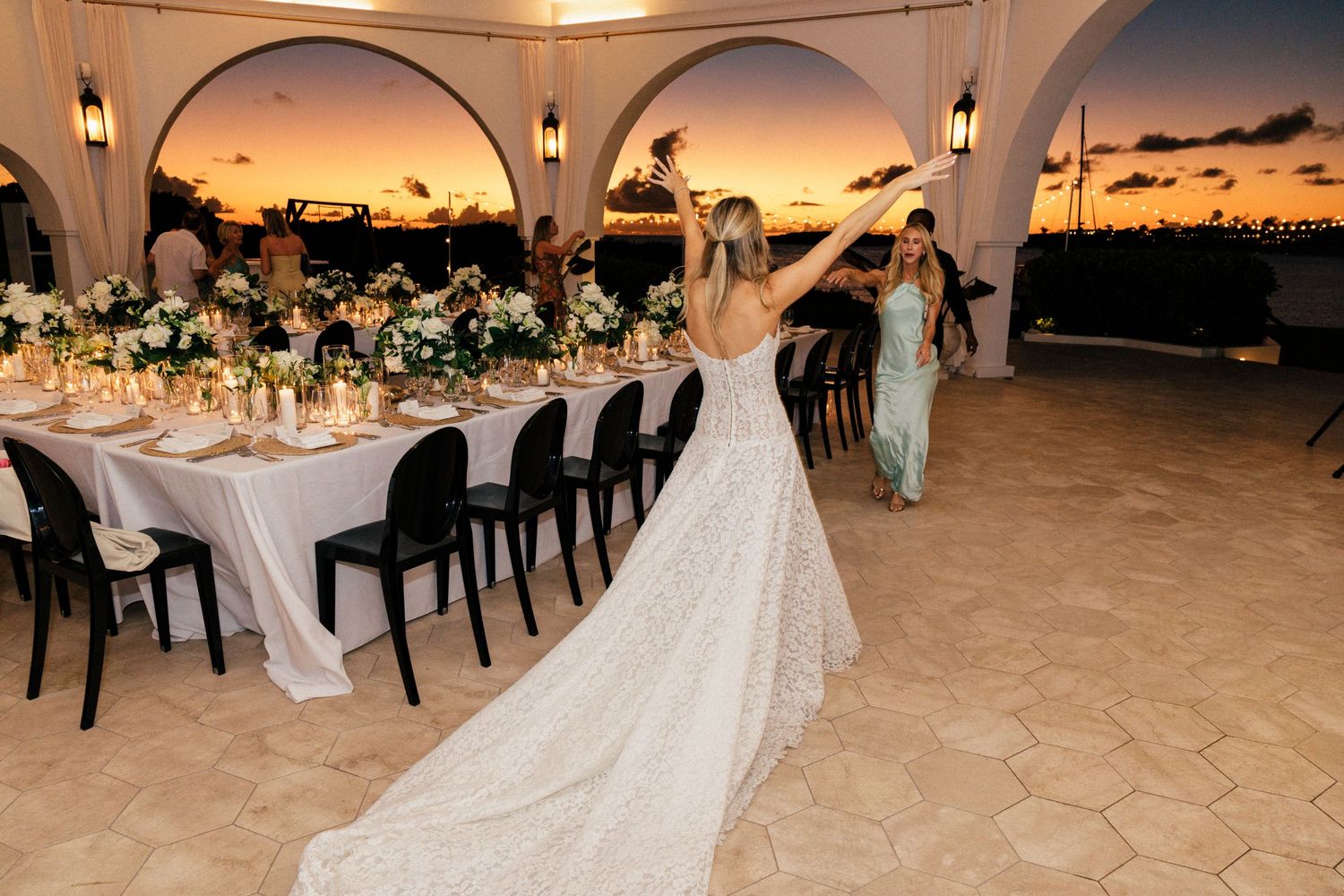 Wedding reception venue with arched columns and elegant table settings at dusk.