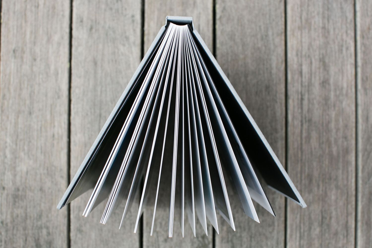 Close-up view of white pages in a wedding album fanning out against a wooden background.