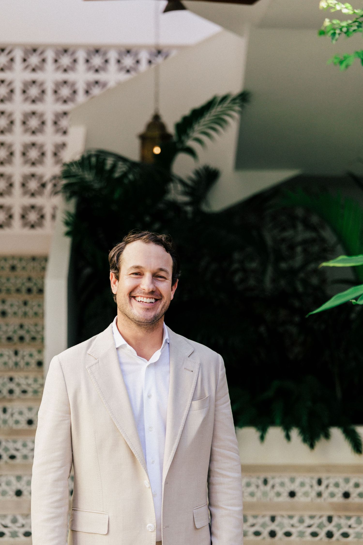A beachside wedding setup with white decor and decorative concrete walls surrounded by tropical plants.