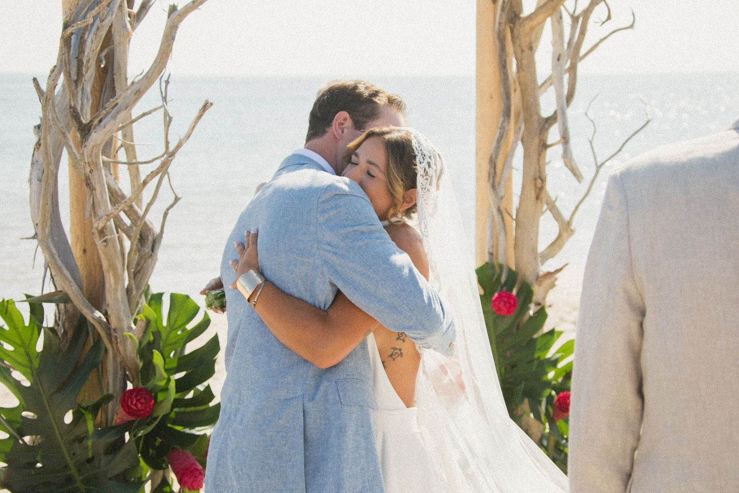 Intimate moments shared between wedding couple during beach ceremony.