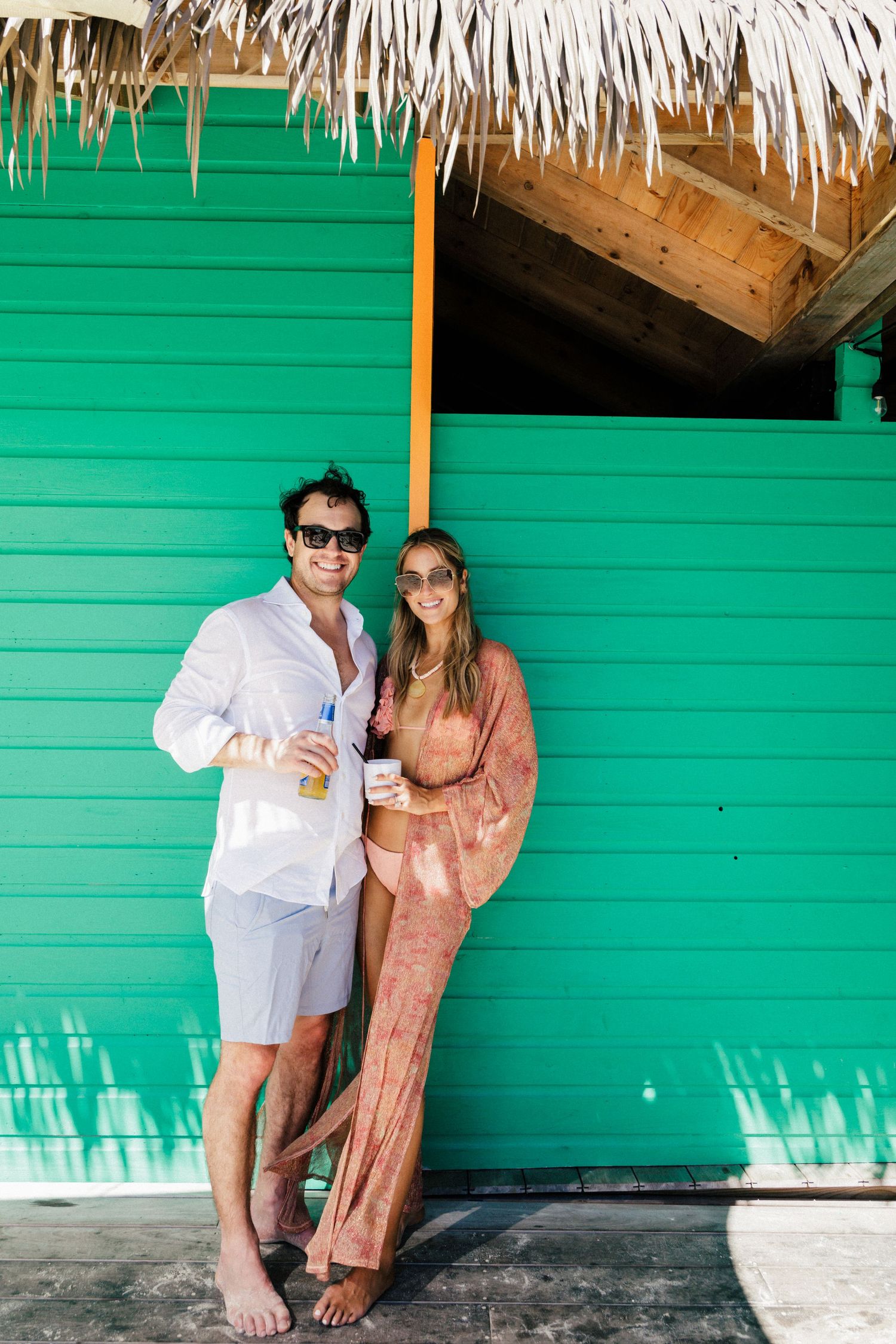 Romantic couple sharing intimate moment against bright green wall at beach resort.