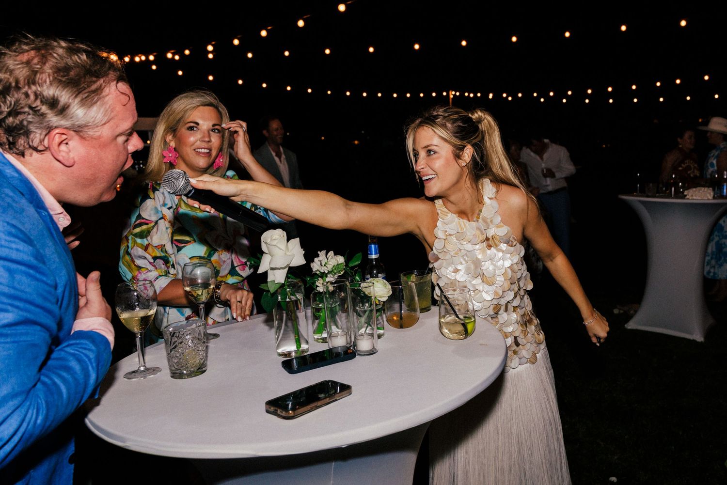 Guests dancing and mingling around tables at an outdoor evening reception.
