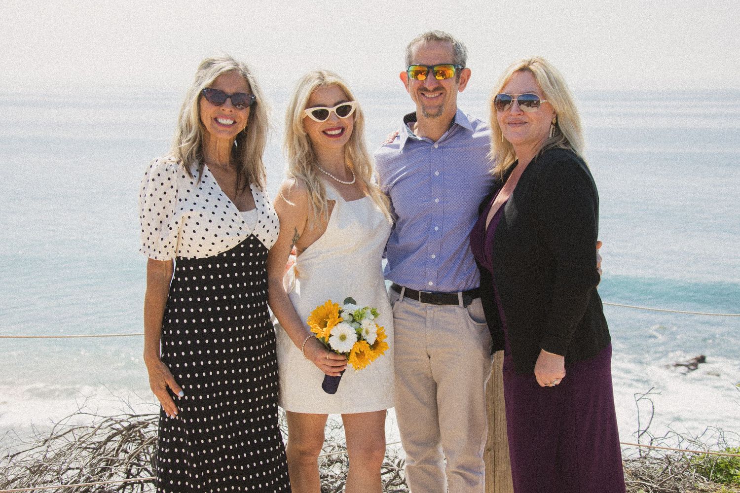 Wedding party members gathered on a coastal path with ocean views.
