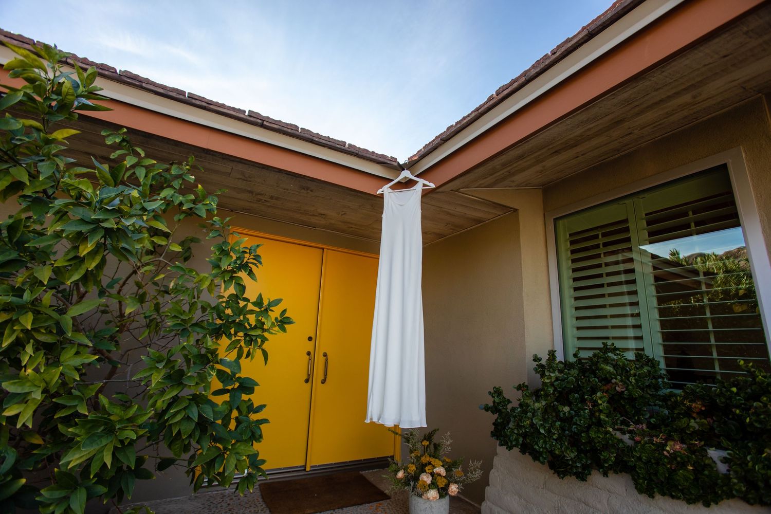 Modern house exterior with yellow walls and white trim under blue sky.