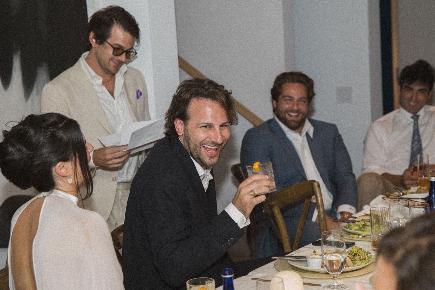 Group of men laughing and enjoying drinks at a formal dinner party event.