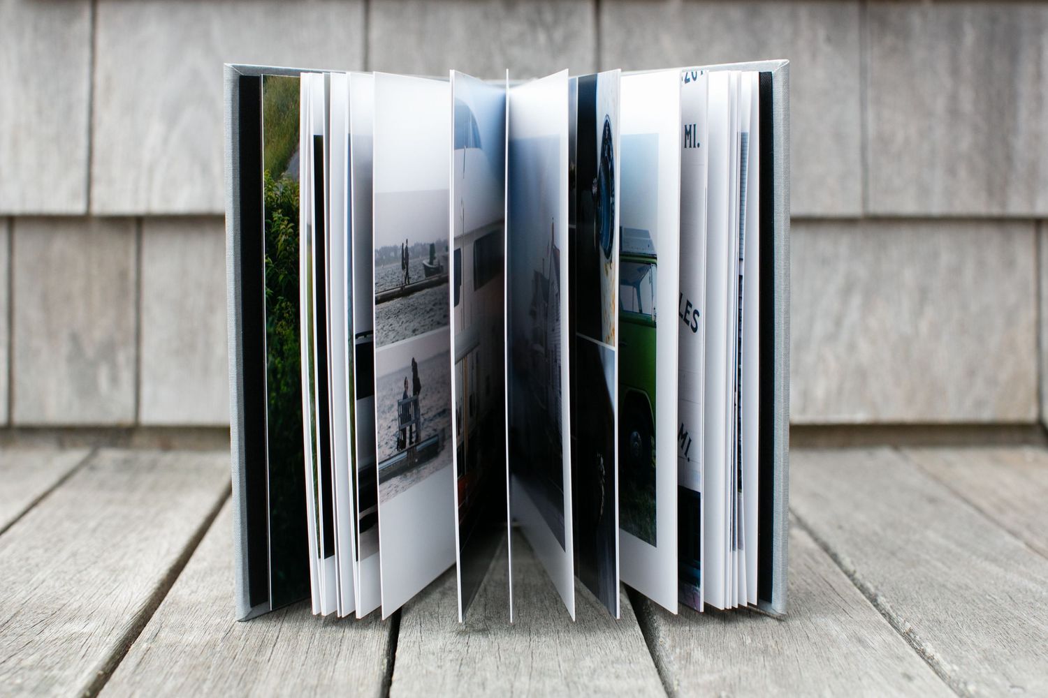 Open photo album with black and white photographs displayed on wooden deck.