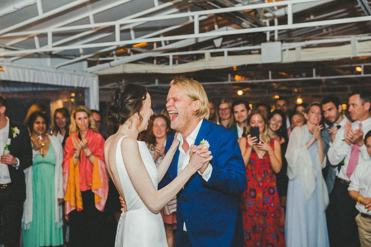 Wedding reception crowd dancing and celebrating on indoor dance floor.