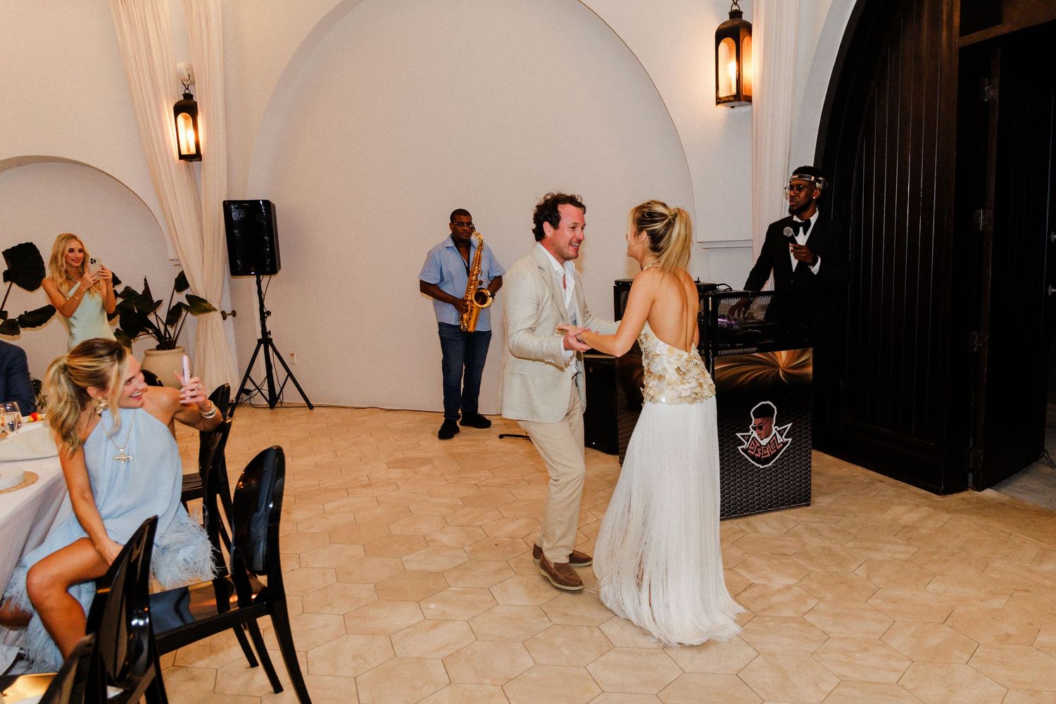 Wedding reception venue with dancing guests and elegant decor under arched ceilings.
