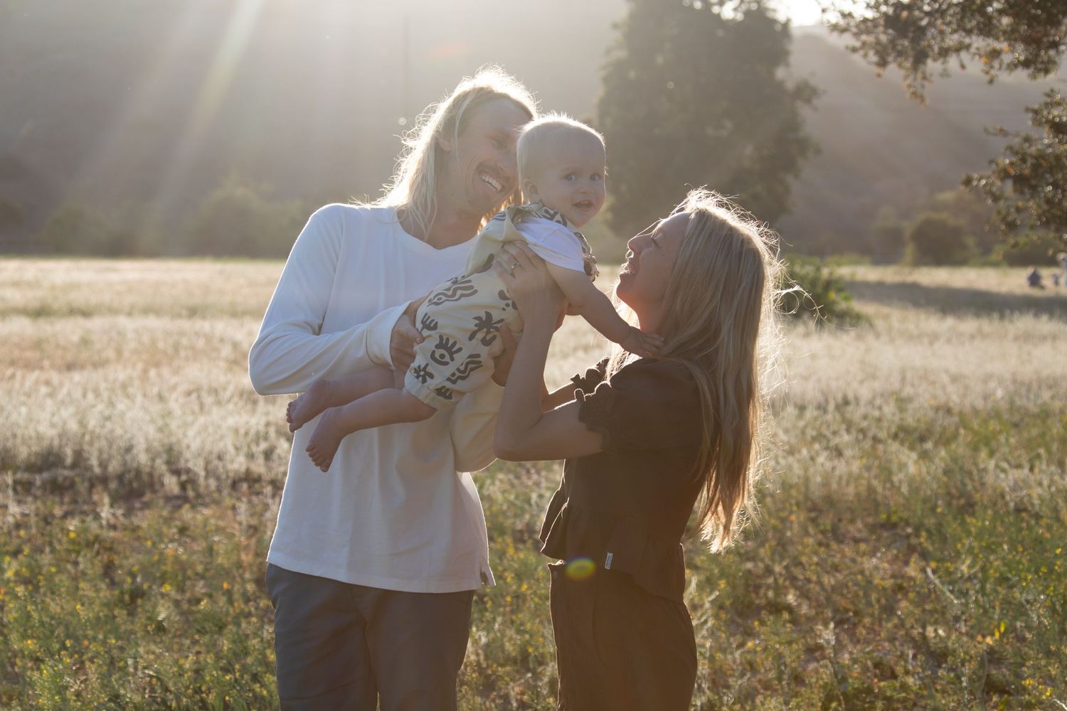 Candid moments captured during a sunset photoshoot in a grassy field.