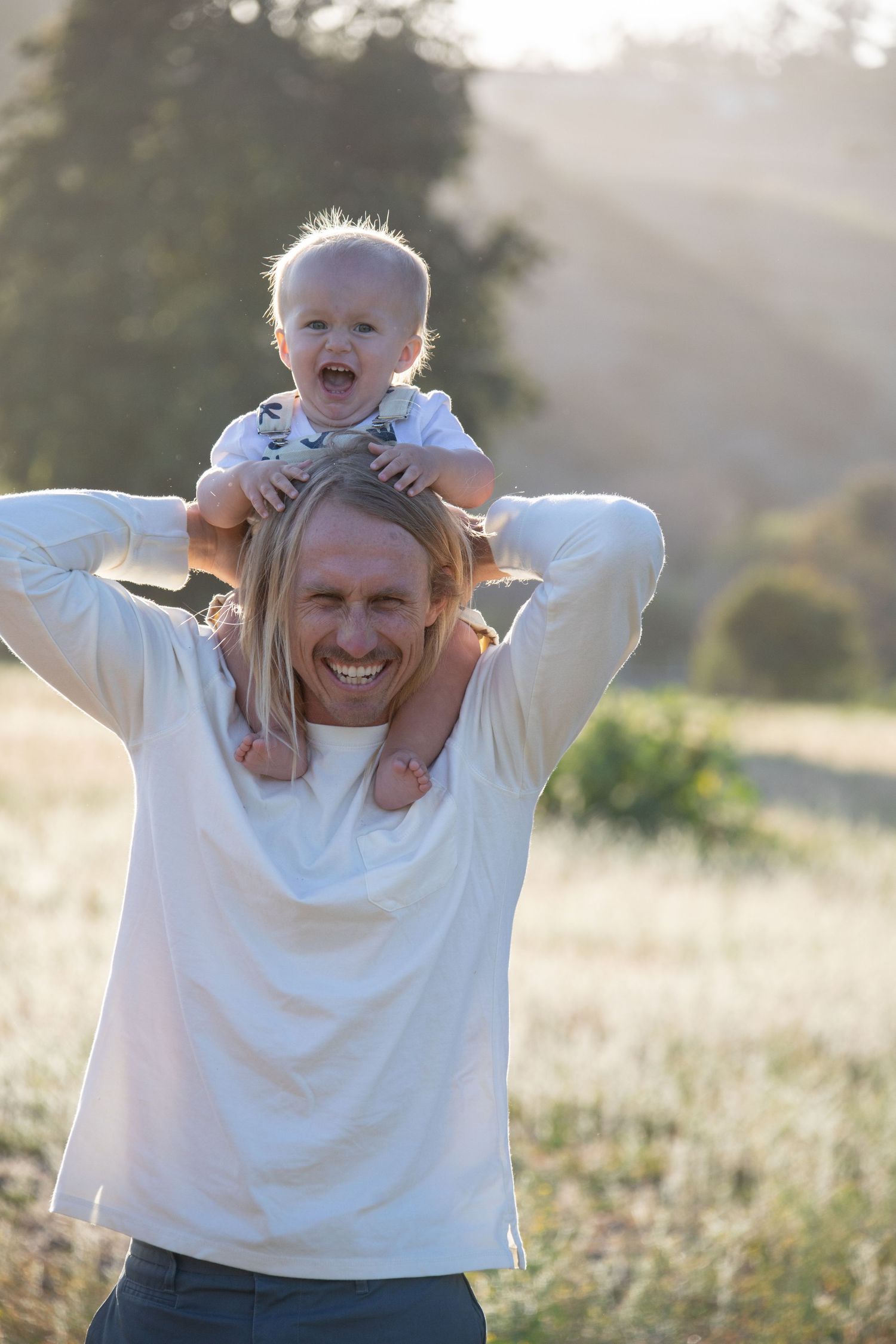 A joyful moment captured as a toddler rides on shoulders in golden evening light.
