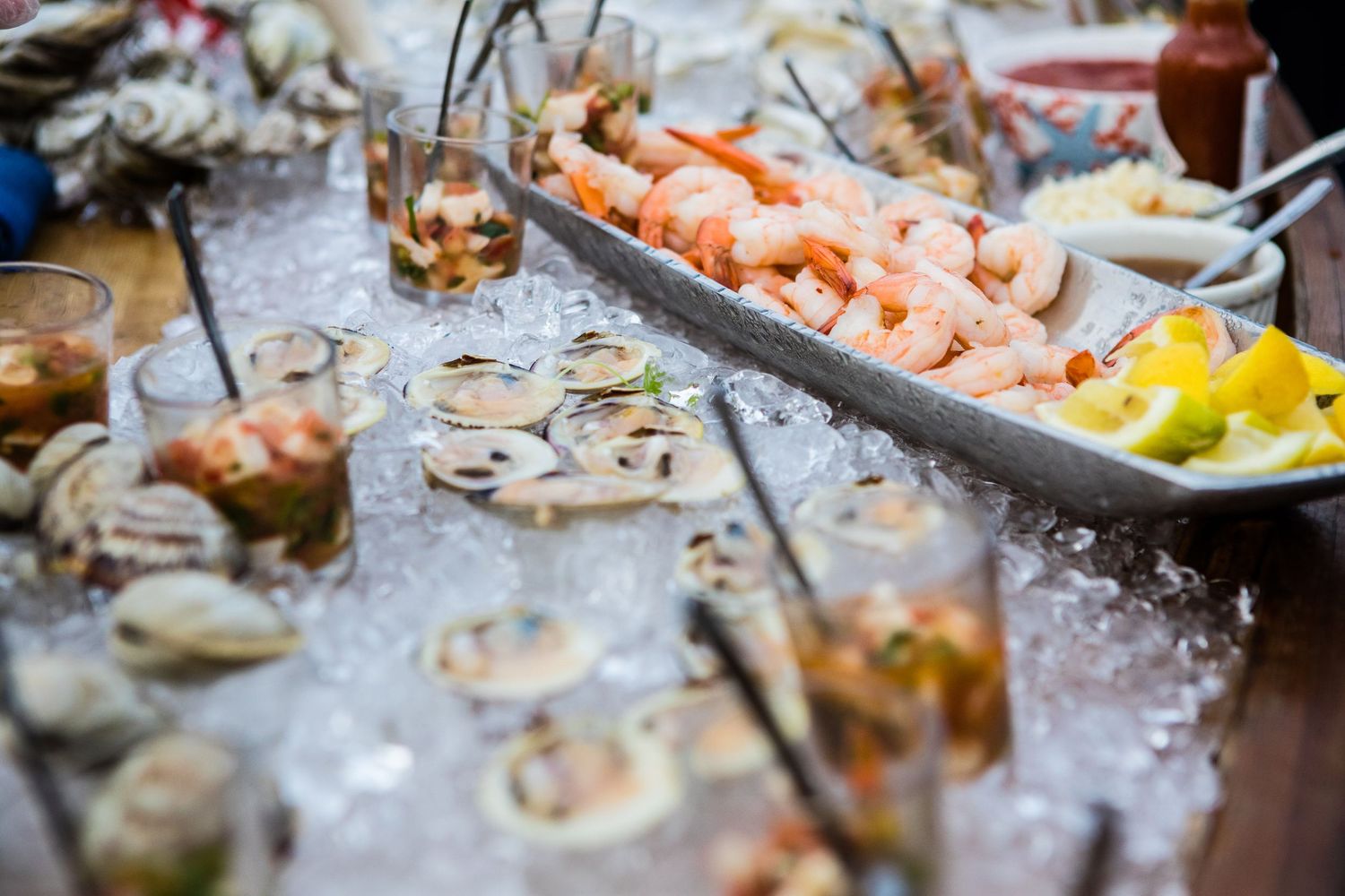 Fresh seafood spread on ice featuring shrimp cocktail, oysters on the half shell, and clams at an elegant buffet.