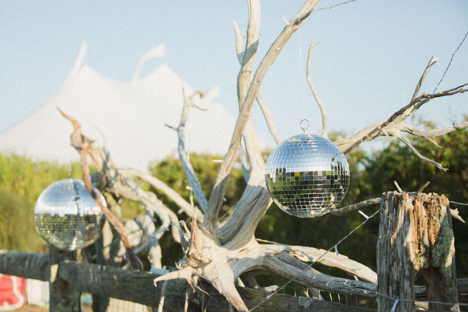Decorative driftwood branches with hanging disco balls create beach wedding decor.