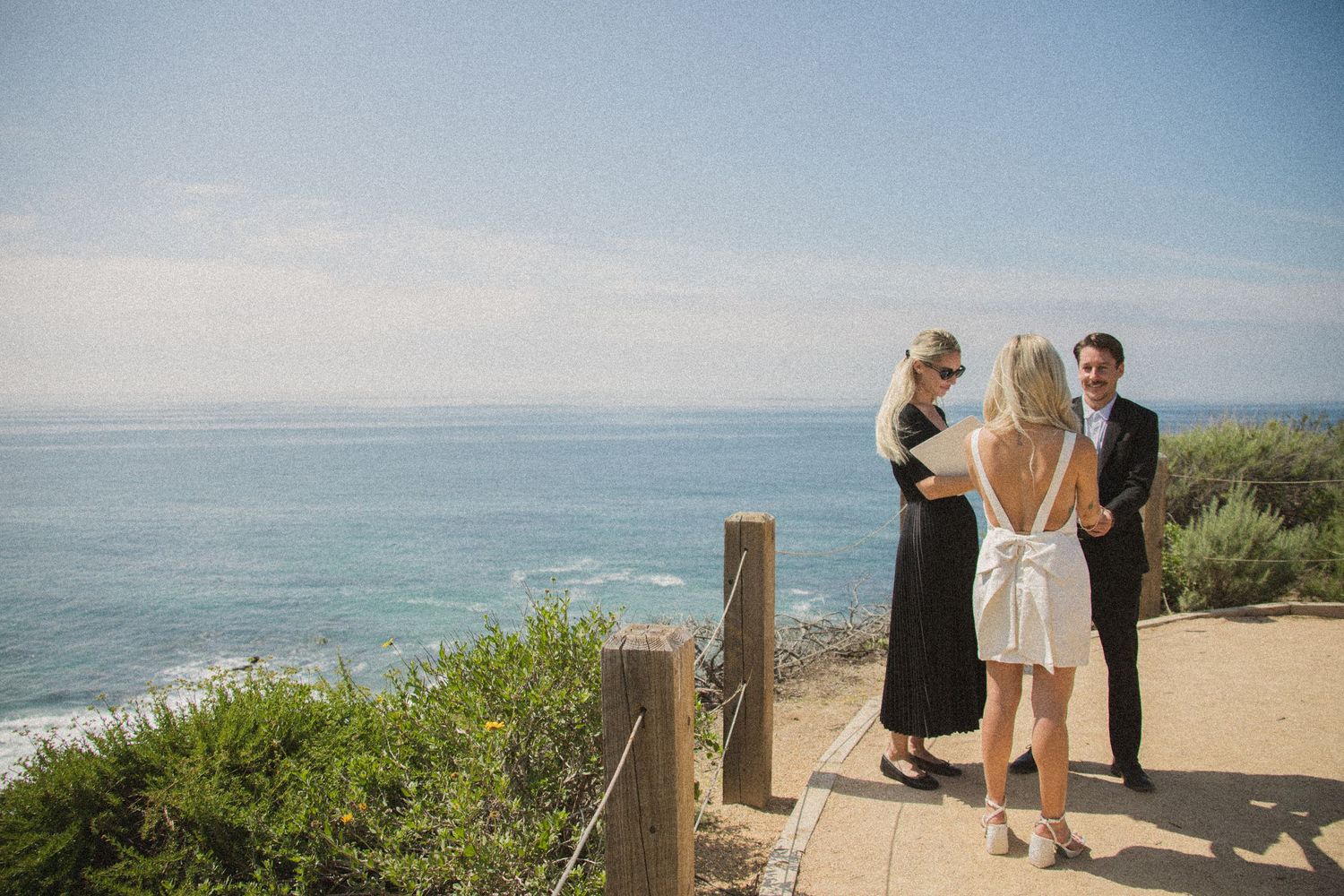 Small wedding gathering on a scenic coastal cliff overlooking the ocean.