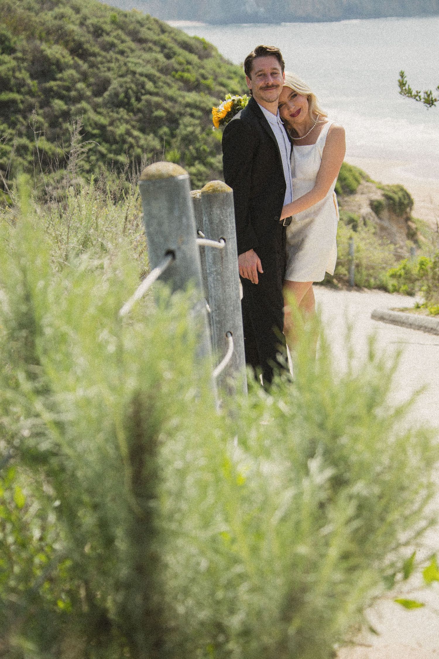 Intimate wedding portraits captured along a scenic coastal path with ocean views.