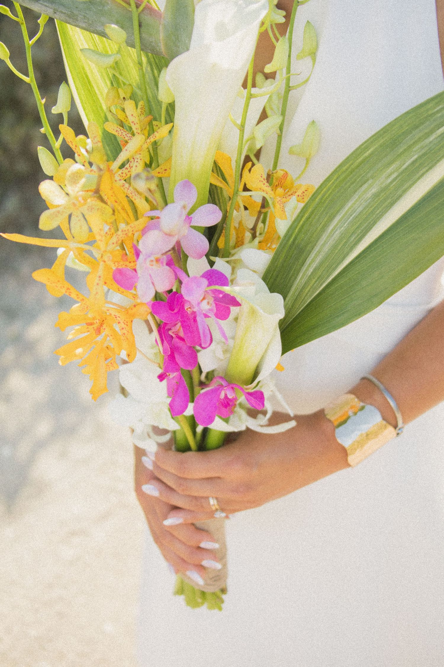 Close-up of a tropical wedding bouquet with yellow orchids and pink flowers.