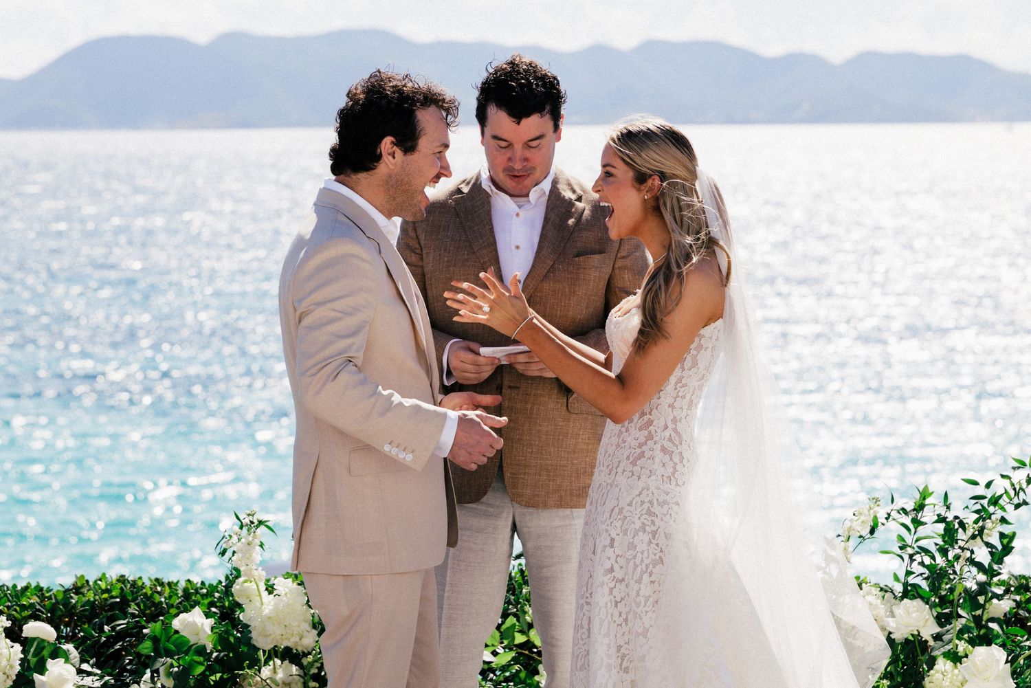Intimate beachfront wedding moment with mountains and ocean creating a picturesque backdrop.