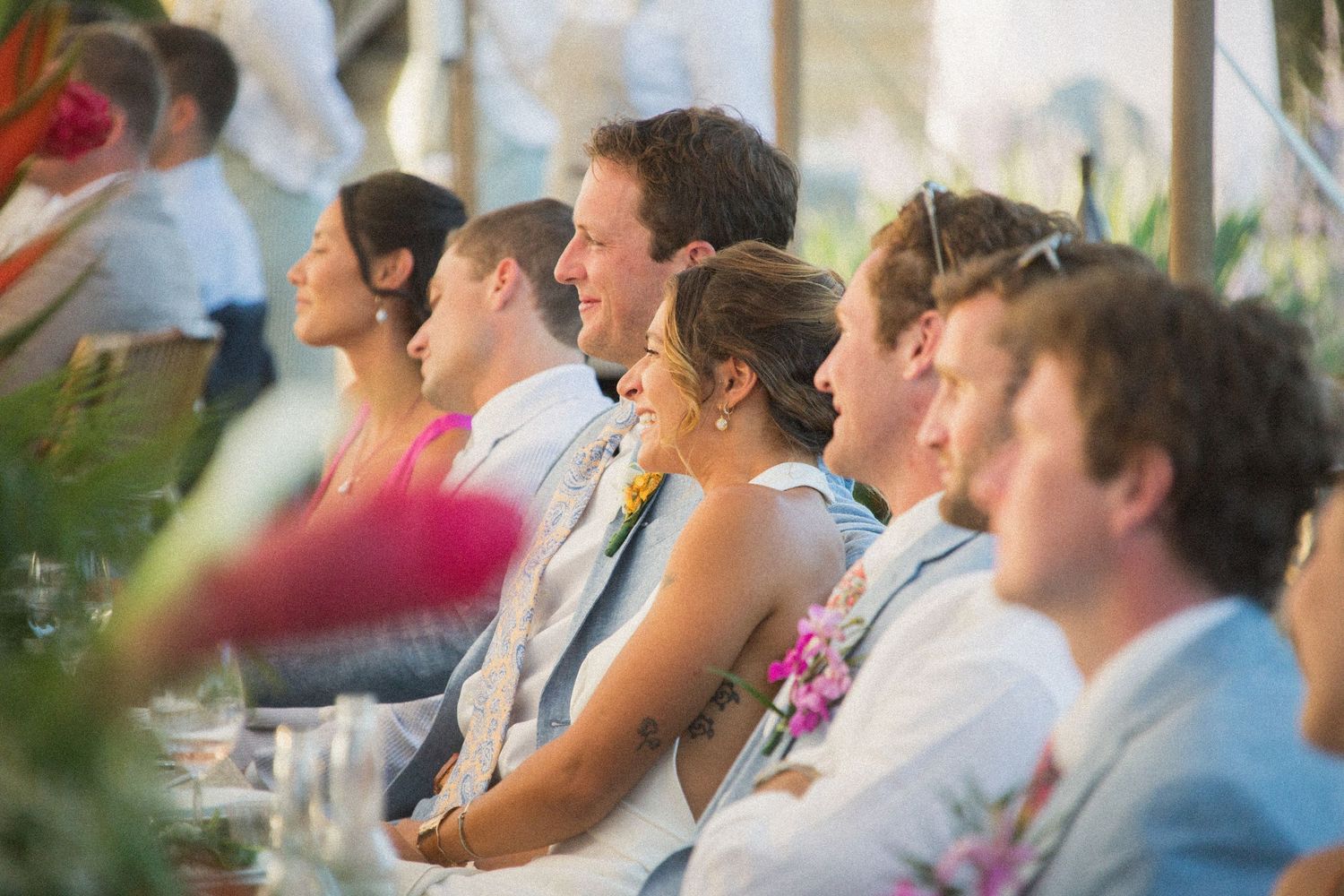 Wedding guests watch attentively during an outdoor reception ceremony.