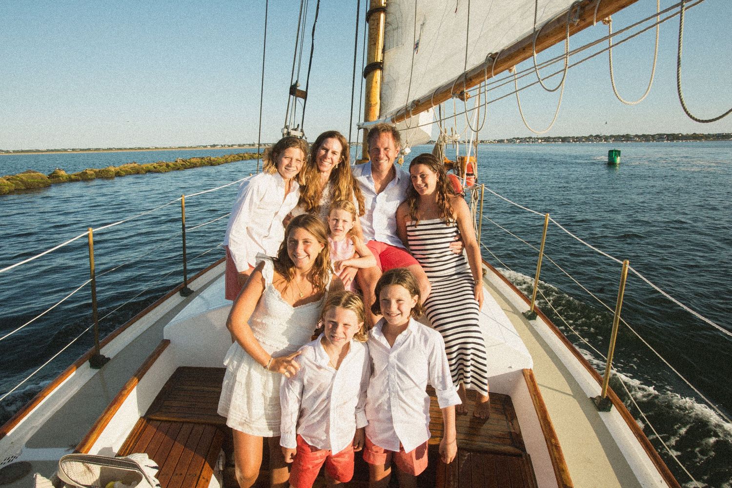 Group enjoying a sunny day aboard a classic sailing vessel on calm waters.