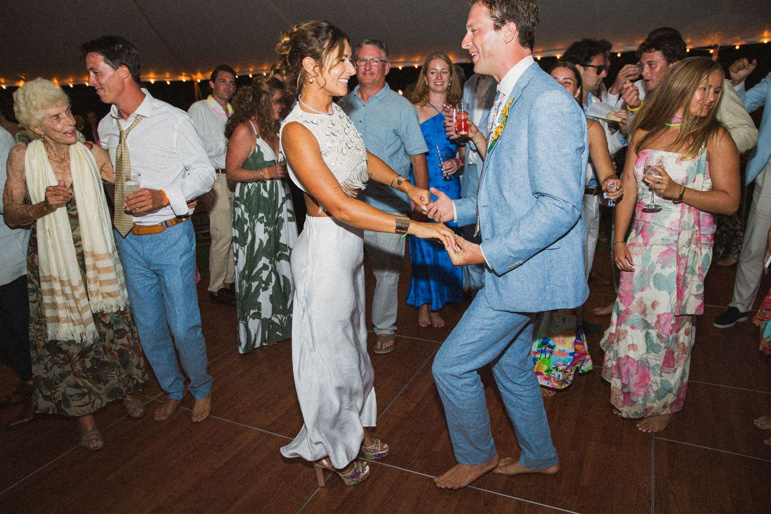 Couples dancing together at a wedding reception on a wooden dance floor.