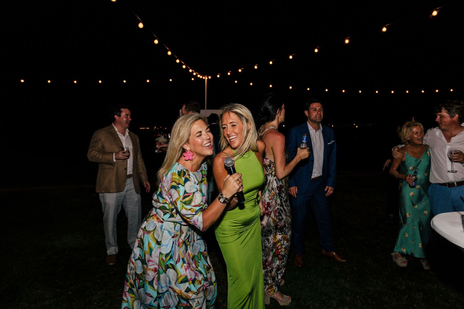 People dancing in colorful attire at an outdoor evening celebration.