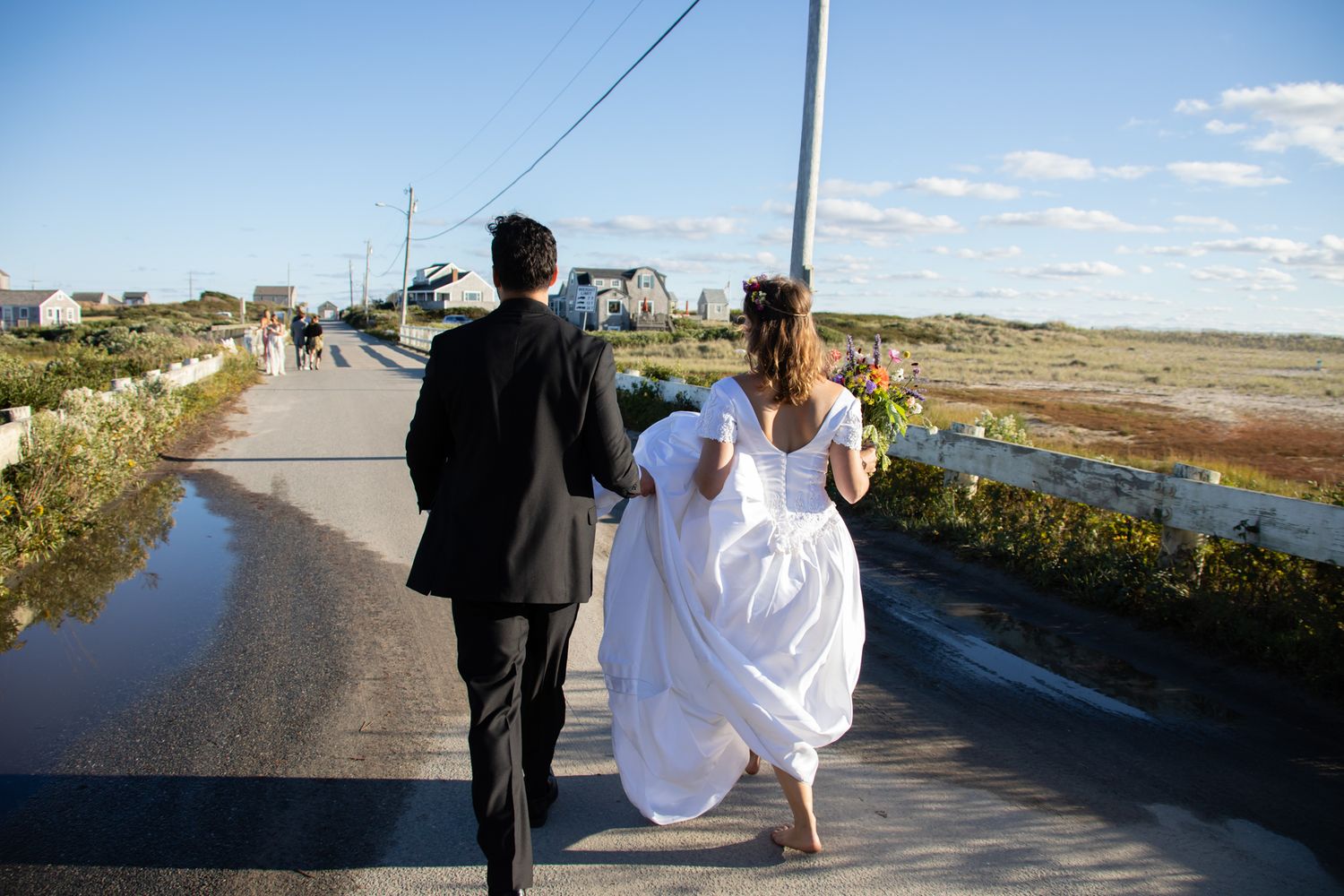 Wedding couple walking along a coastal path with scenic water views.