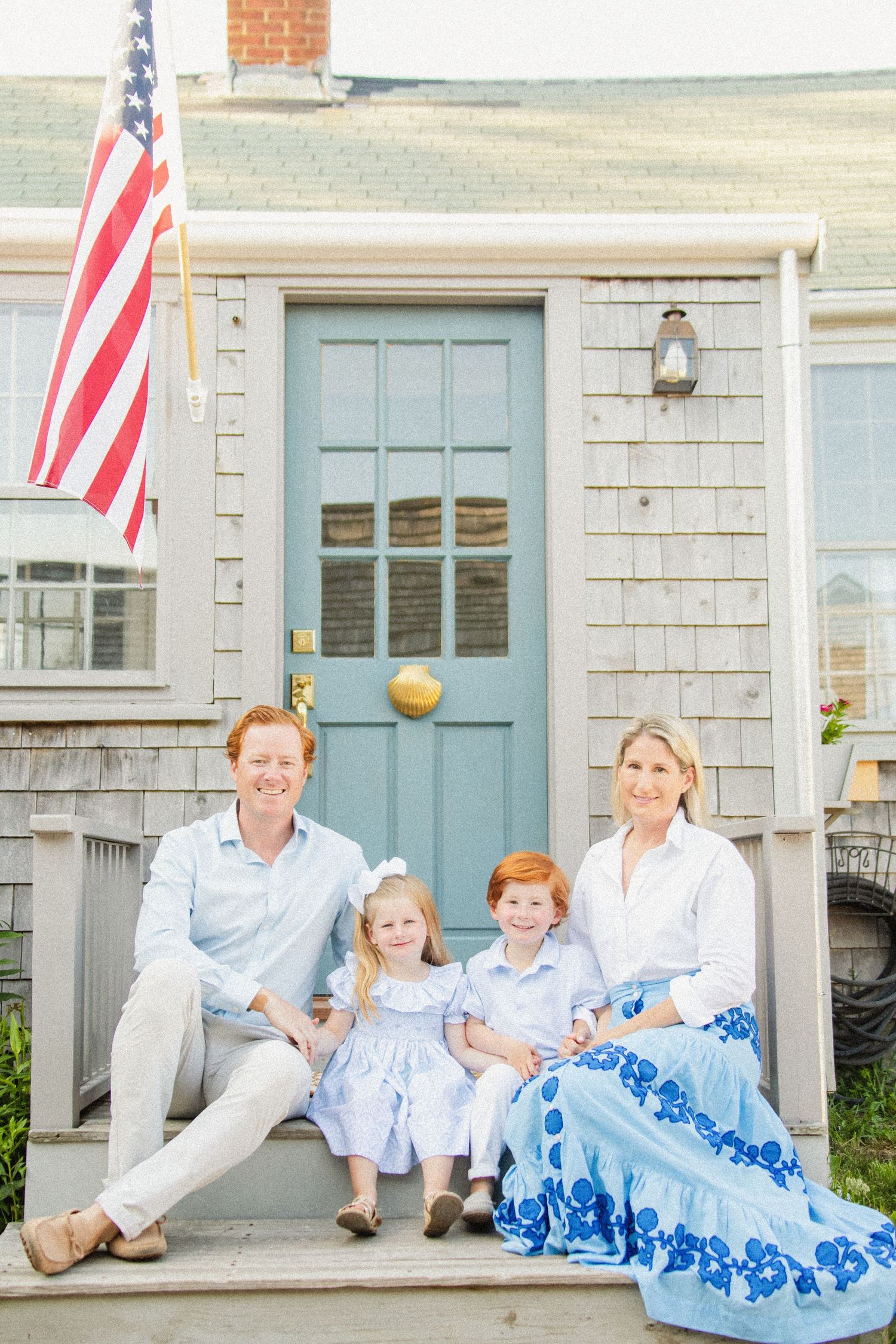 Patriotic family photo session on a porch with American flags and blue accents.
