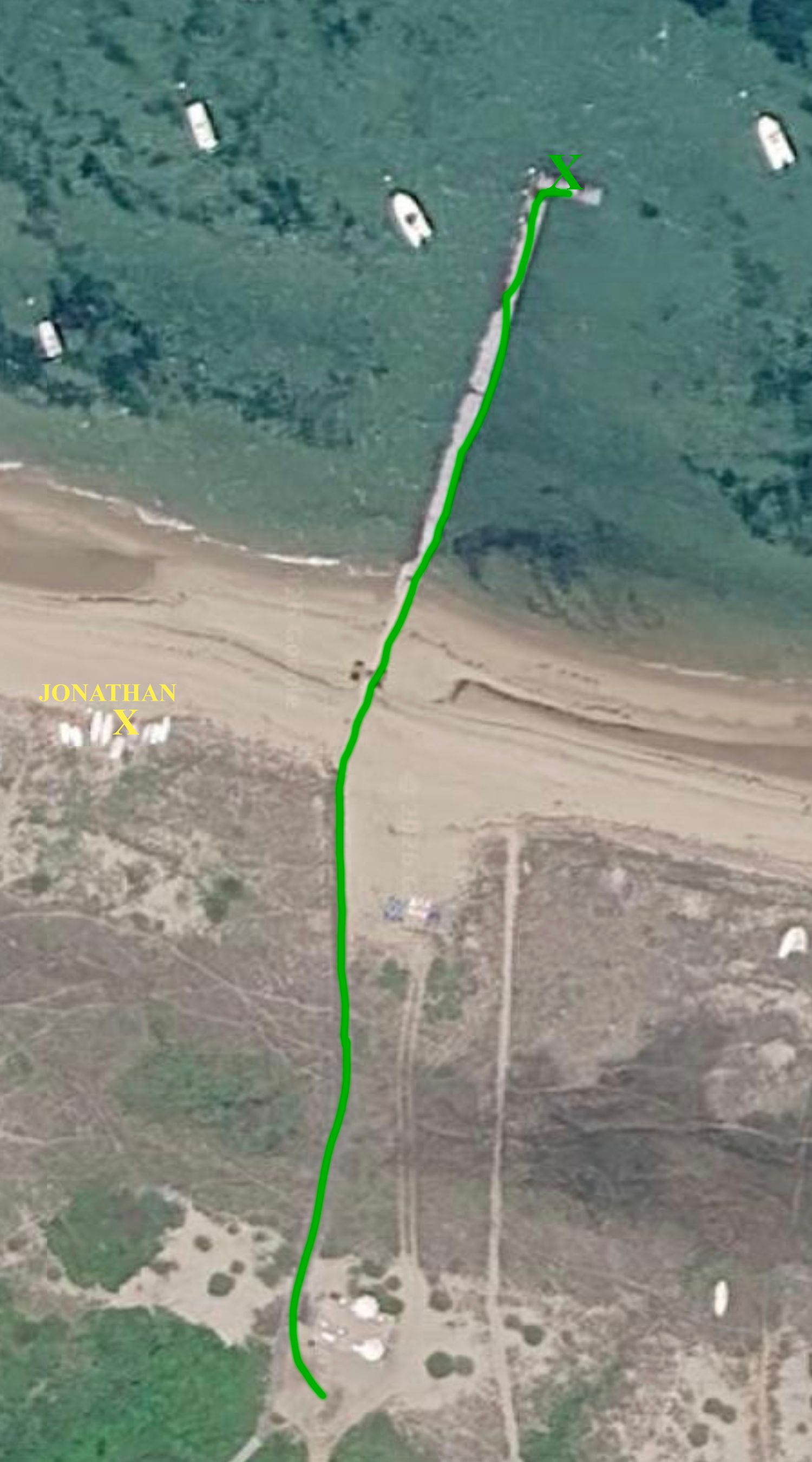 Aerial satellite view of a coastal beach path marked with a green GPS trail line leading to the water's edge.