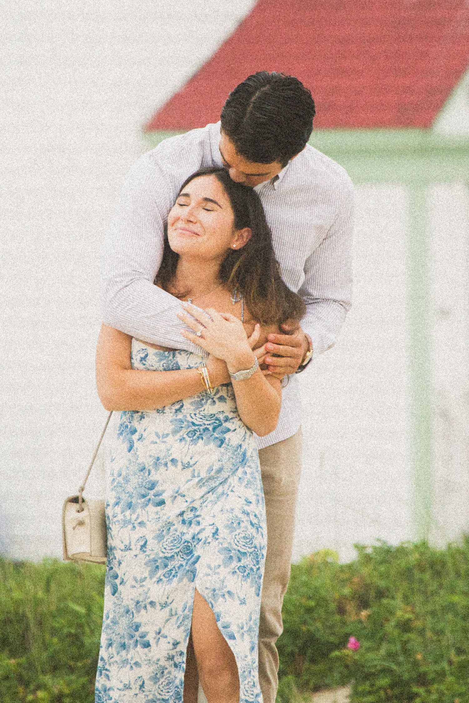Playful couple sharing intimate moment against red and white building.