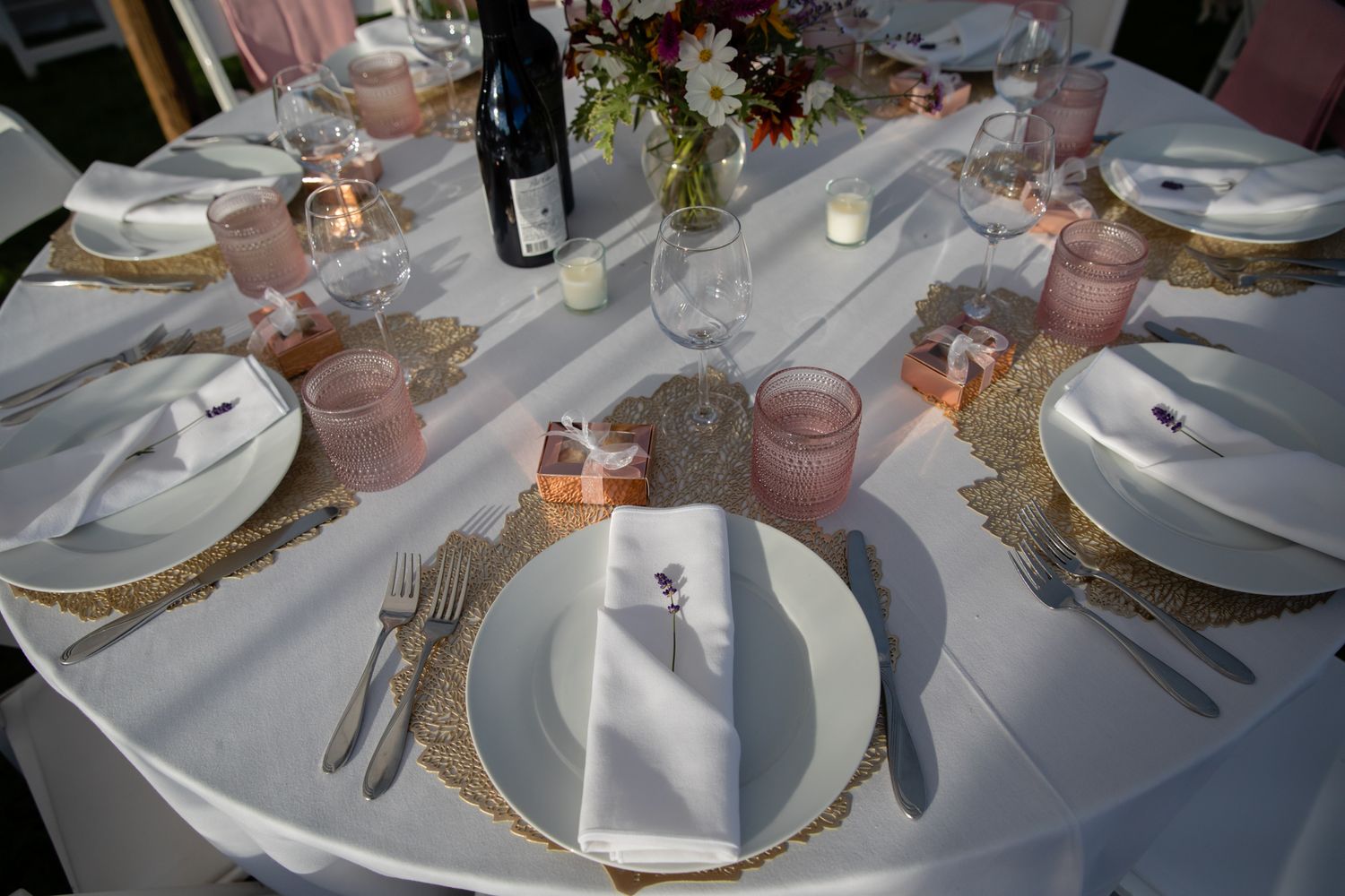 Elegant table settings with pink and gold accents at a wedding reception.