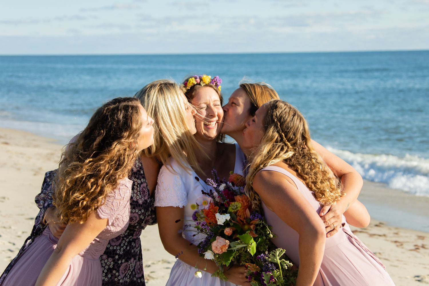 Intimate beach wedding photos with bright bouquets and ocean backdrop.