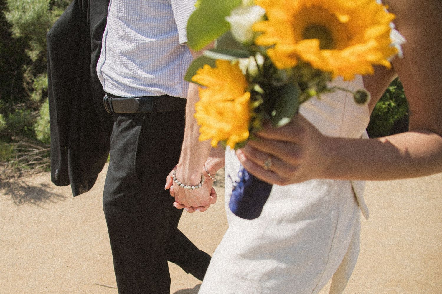 Close-up of bright yellow sunflowers being held during a beach wedding ceremony.