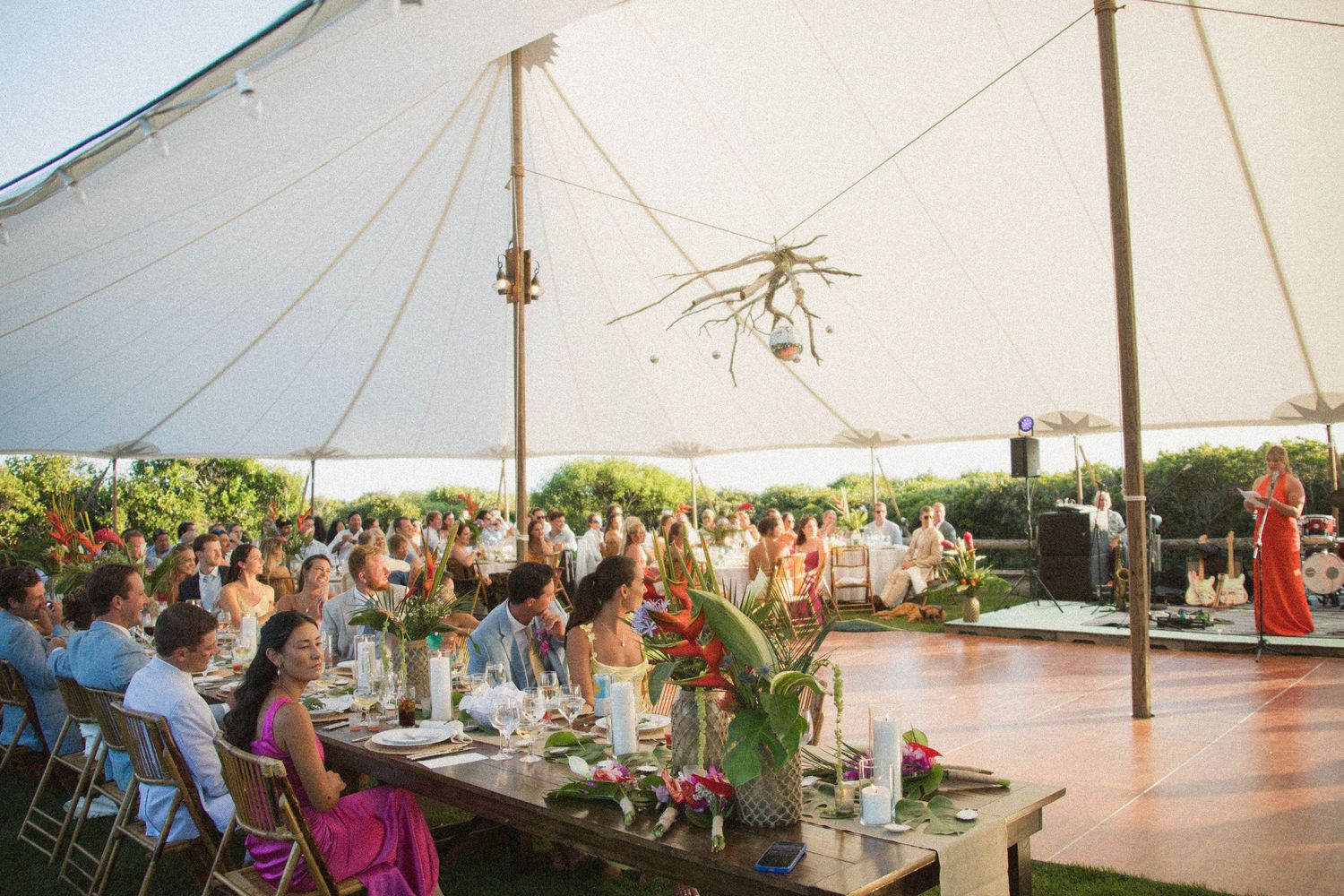 Large white tent set up for an elegant outdoor wedding reception with guests seated at tables.