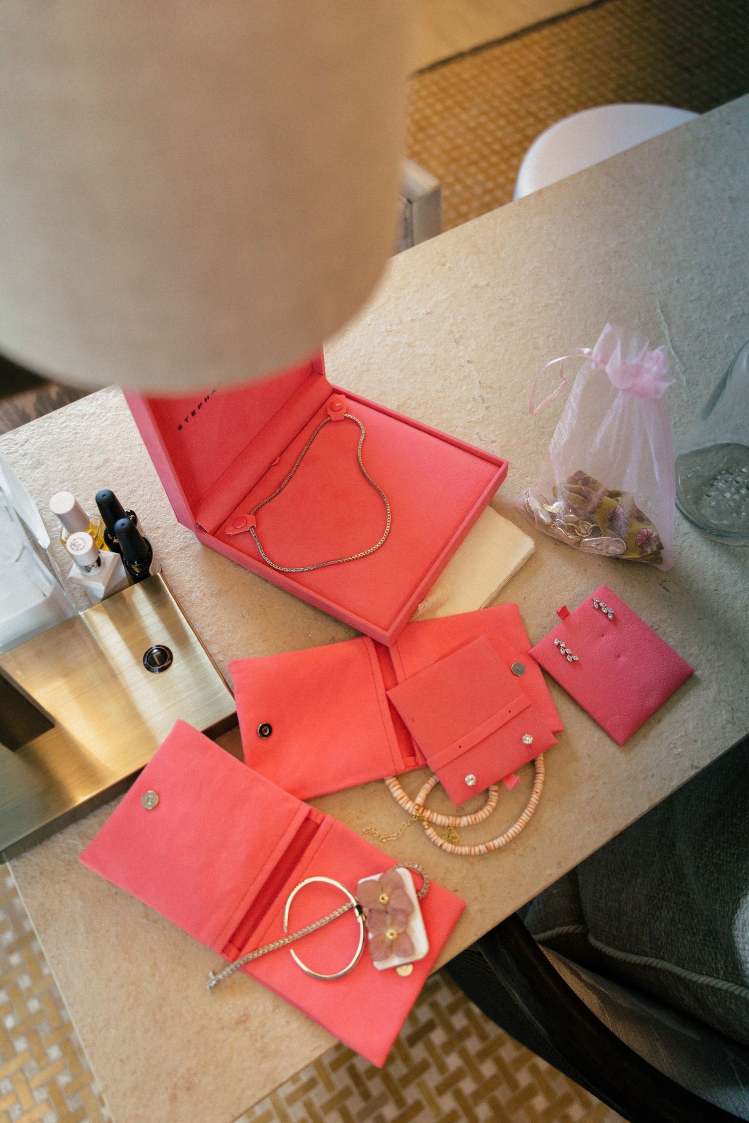 Pink bridesmaid gift bags and jewelry laid out on beige counter.