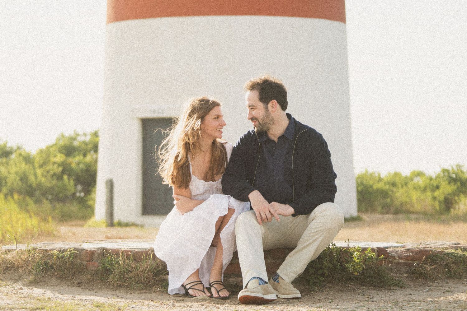 Relaxed outdoor photography session with a couple against a neutral wall.