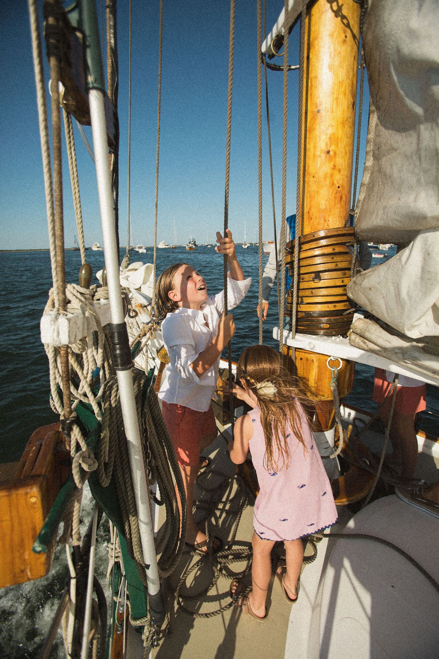 View of wooden mast and rigging details on a classic sailboat during daytime.