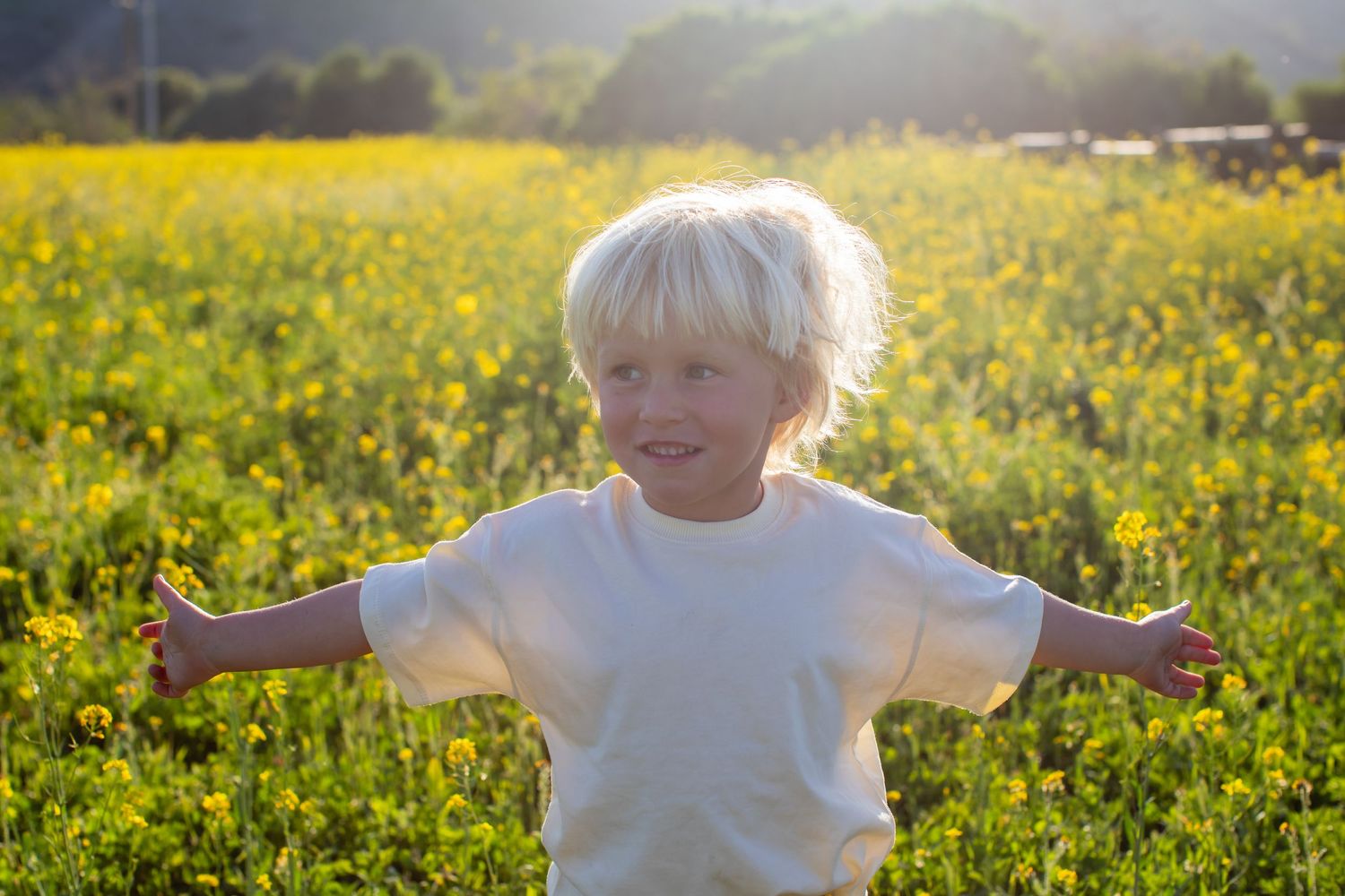 Child playing and running through a field of bright yellow wildflowers.