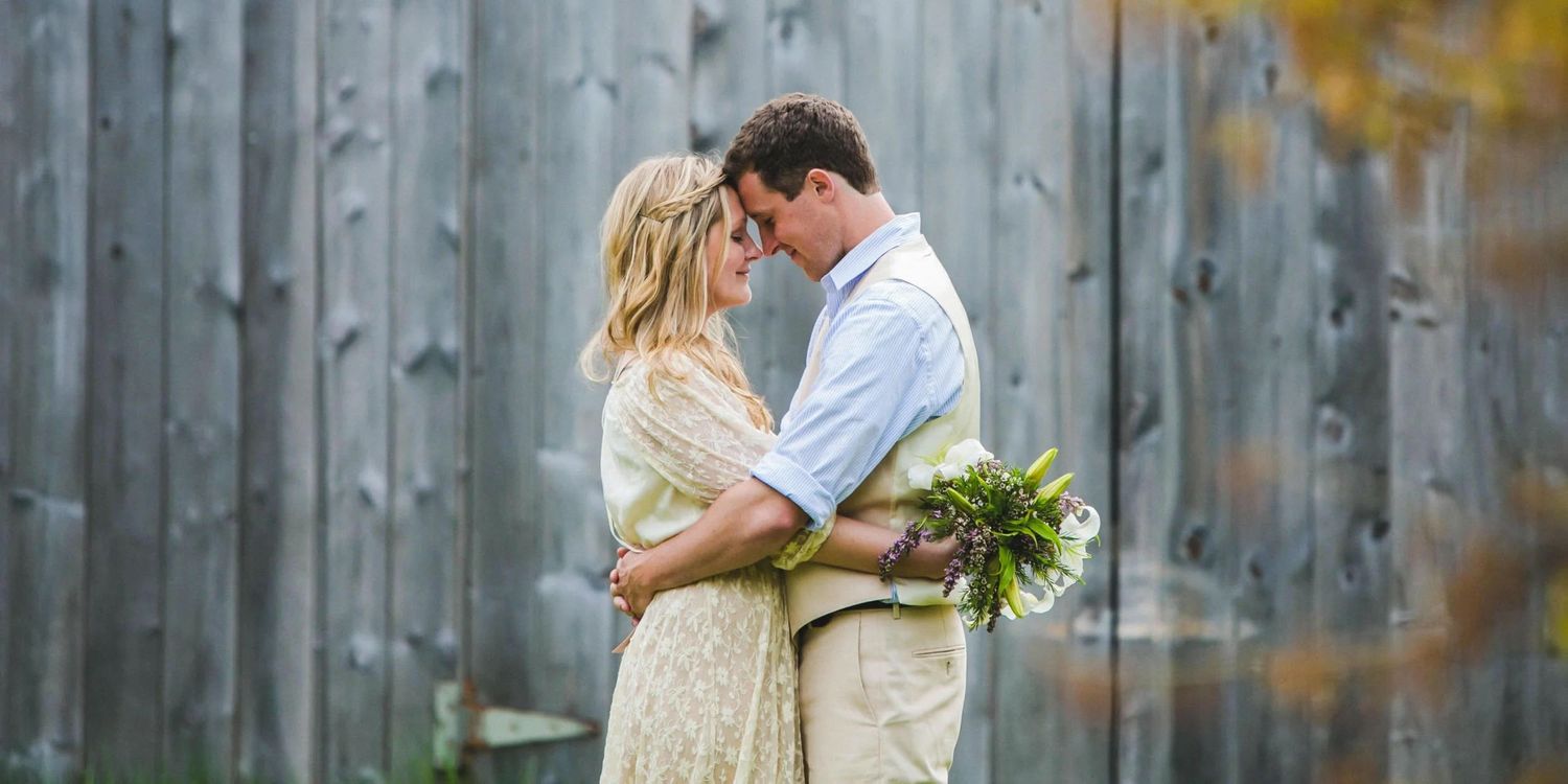 Romantic moment shared against a weathered wooden barn wall backdrop.